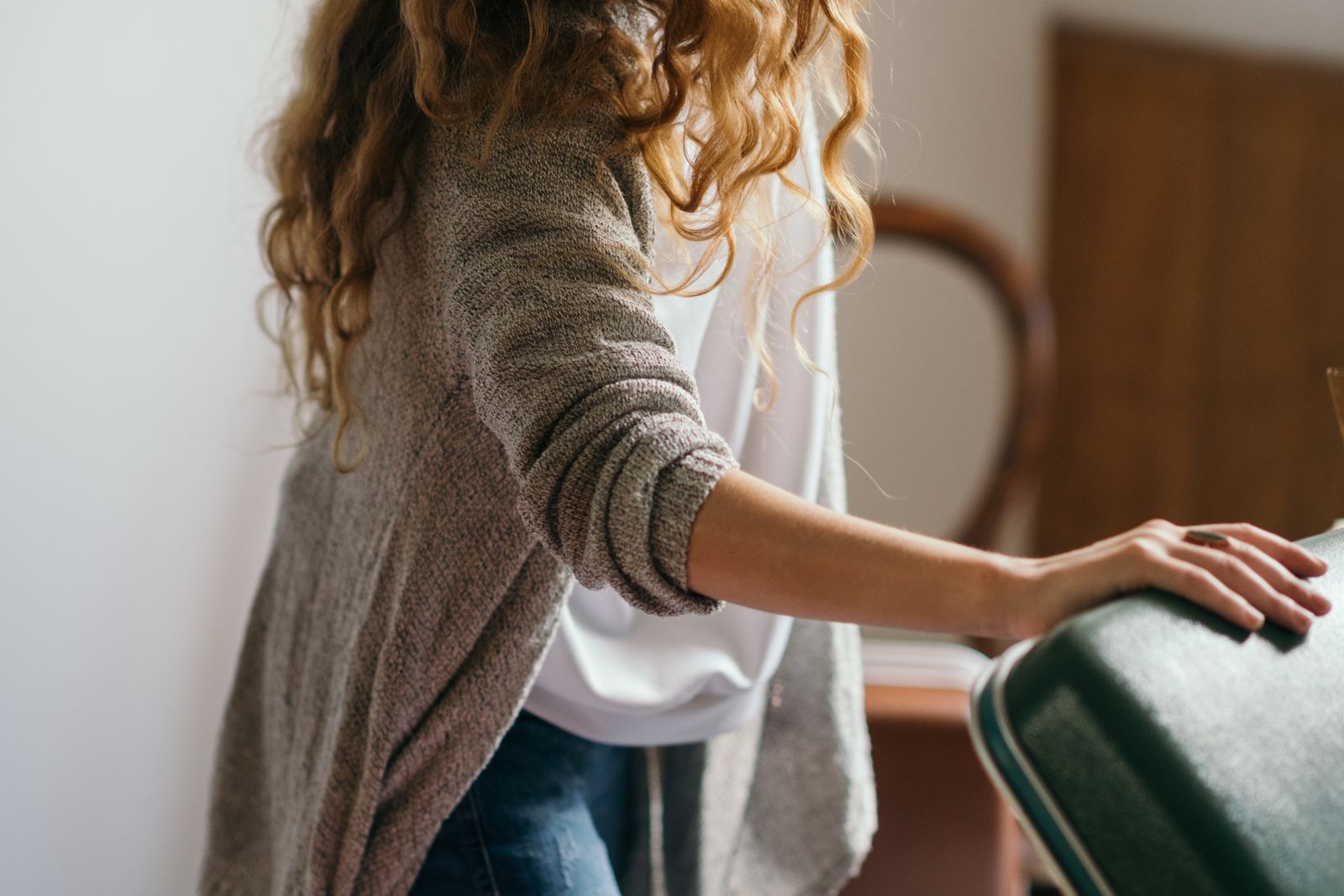 Une personne posant la main sur une valise, en train de préparer ses bagages avant le départ en vacances